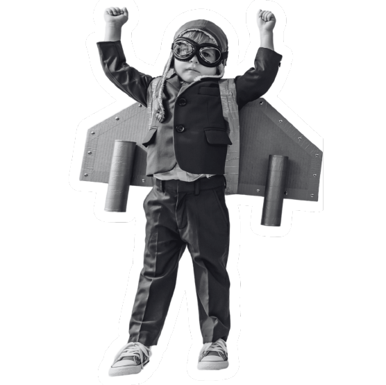 A boy in aviator goggles with cardboard rocket wings, arms up
